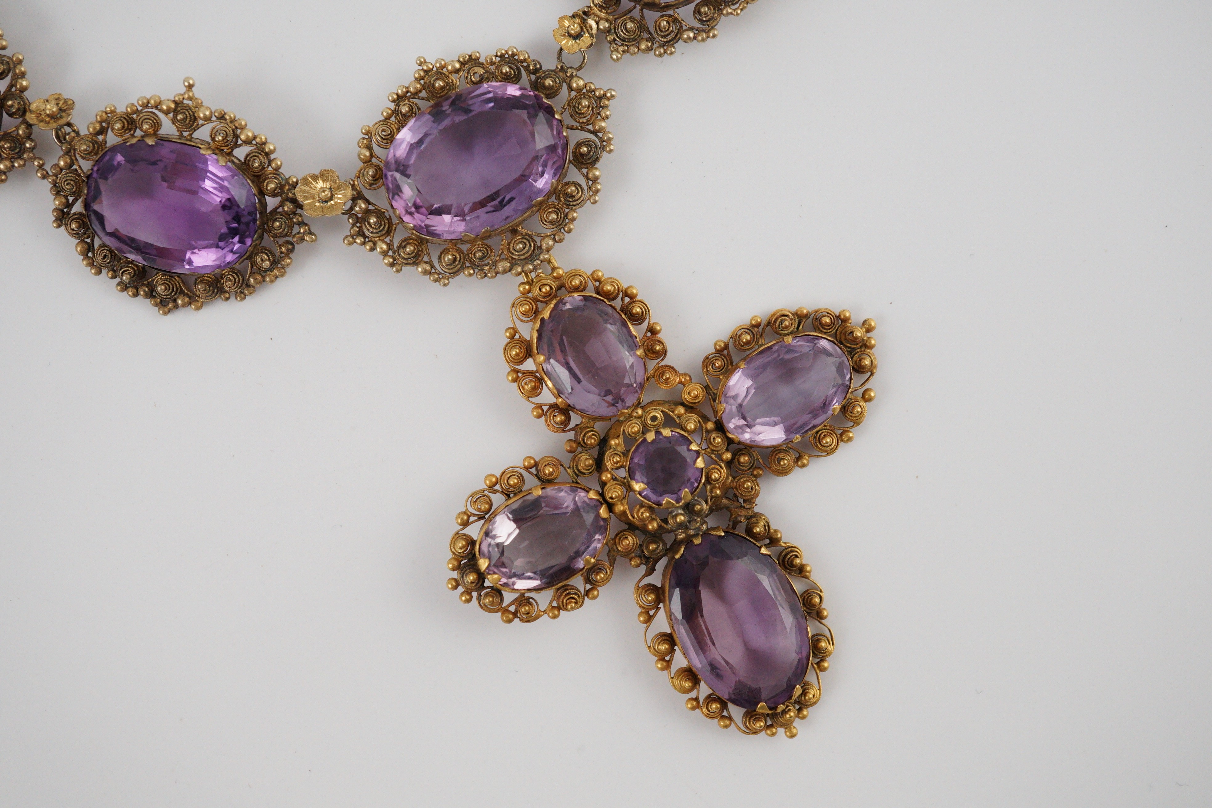 An early 19th century gold and eleven stone oval cut amethyst set pendant necklace and a similar cross pendant (repair)